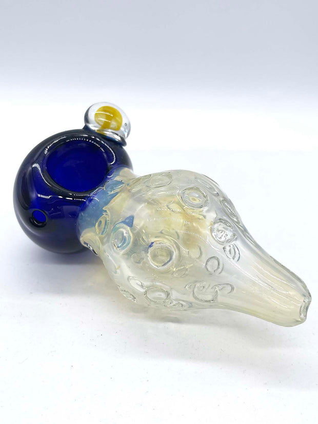 Photo of a large fumed spoon pipe with a blue head and a bulbous fumed body that tapers to a small mouthpiece, against a white background. The mouthpiece is facing forward right, and a mushroom implosion bubble can be seen on its right side (facing camera).