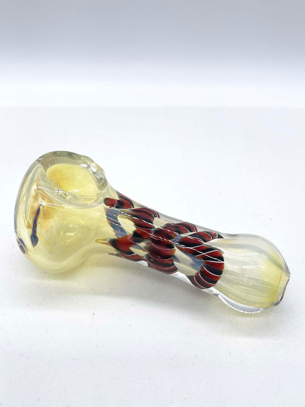 Photo of a glass spoon against a white background. Opposite angle shot of the same piece from the previous photo. The piece has a round bowl and a long body that is thinner in the middle. The piece has a milky sheen to it, and there is red ribbon coiled in the middle.