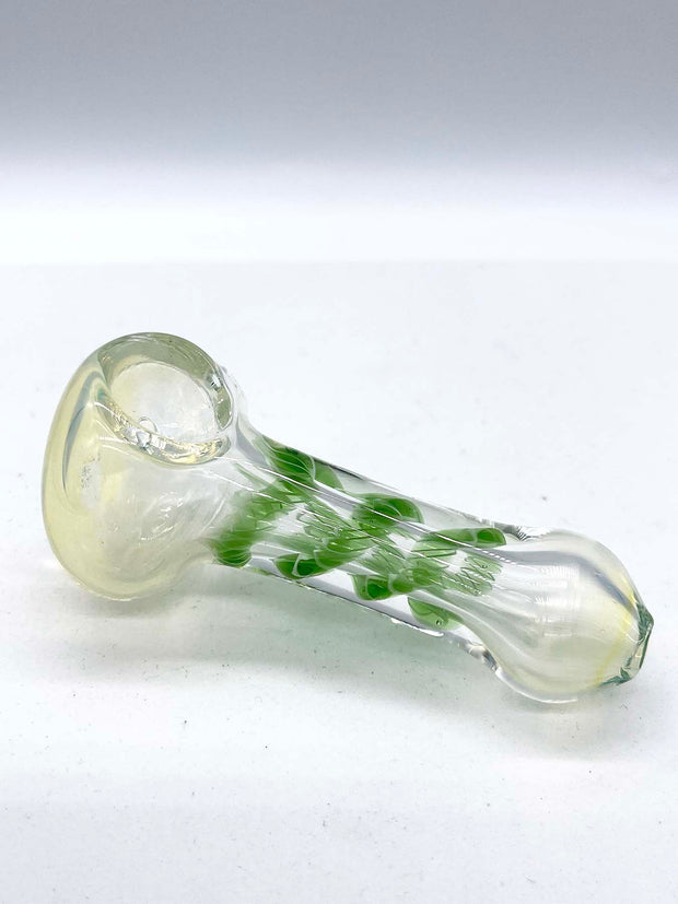 Photo of a glass spoon against a white background. This is the same piece shot from the opposite angle.  The piece has a round bowl and a long body that is thinner in the middle. The piece has a milky sheen to it, and there is green ribbon coiled in the middle.