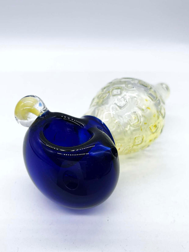 Photo of a large fumed spoon pipe with a blue head and a bulbous fumed body that tapers to a small mouthpiece, against a white background. The piece is facing head side left, and a mushroom implosion bubble can be seen on its left side (facing camera).